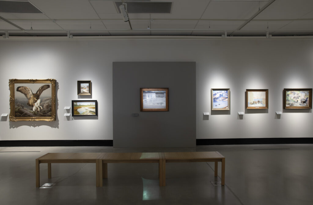 Juuret-näyttelyssä Keitele-maalaus sekä muita maalauksia seinällä.