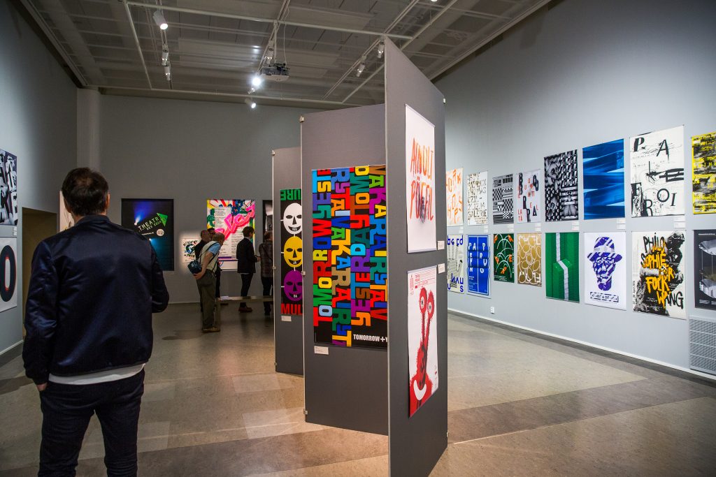 Man walking through hall, which has posters on its walls.