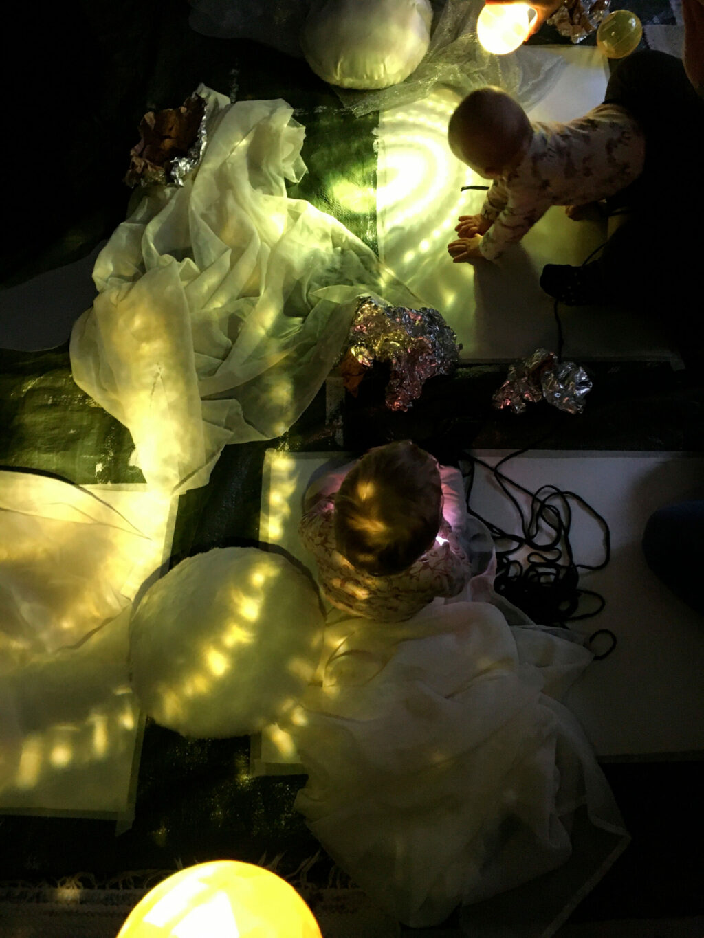 Pieni lapsi tutkimassa kankaita ja pehmeitä materiaaleja.