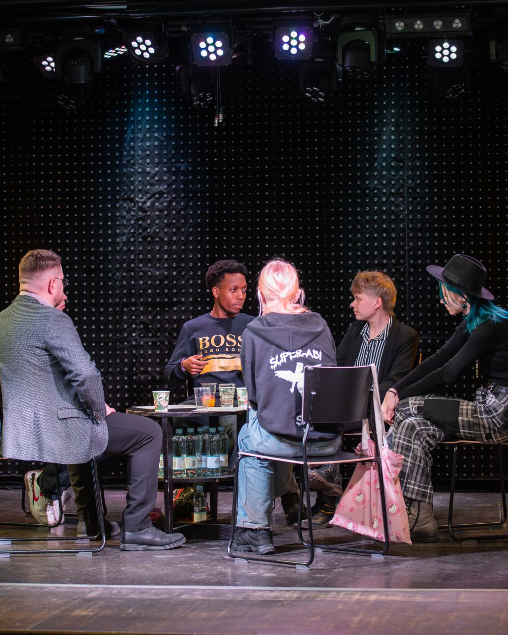 Viisi henkilöä keskustelee pöydän ääressä.