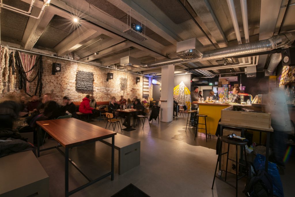 The interior of a pub, people sitting at tables.