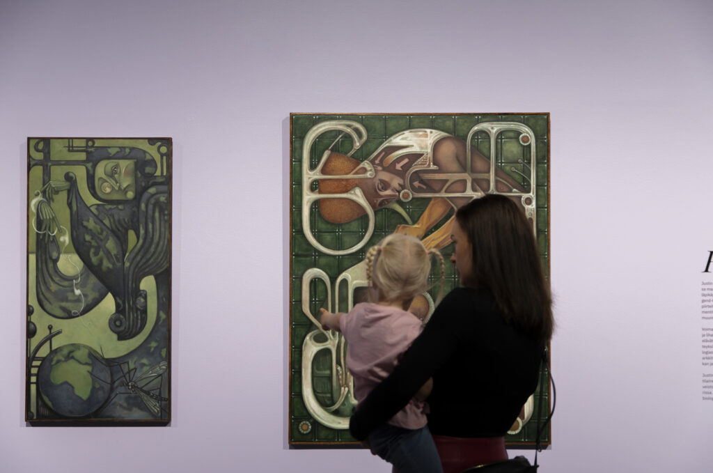 Aikuinen ja lapsi katsomassa maalausta käsi kädessä.